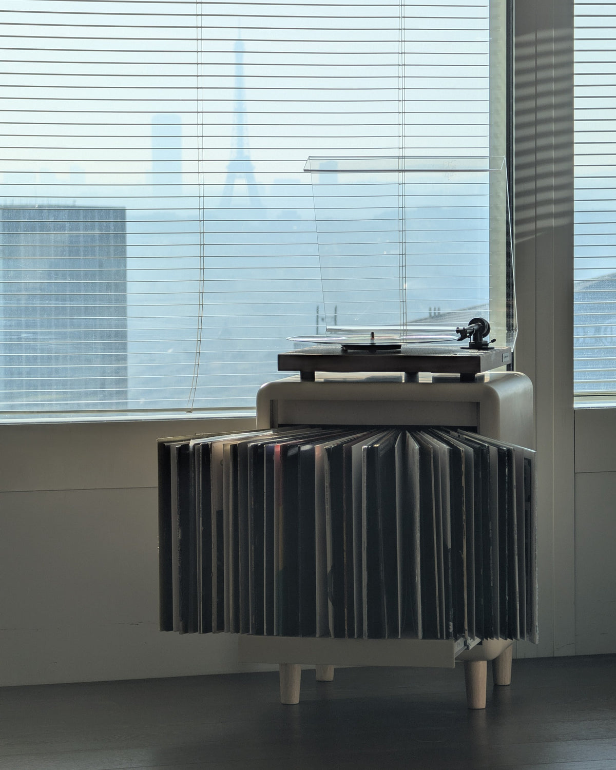 Groovaly Otis vinyl record furniture with records fanned open, in a Paris interior with the Eiffel Tower in the background.
