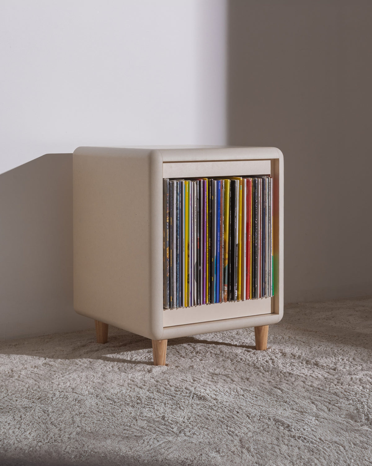 Otis vinyl furniture in White Pearl on wooden feet, filled with records, three-quarter view — Groovaly