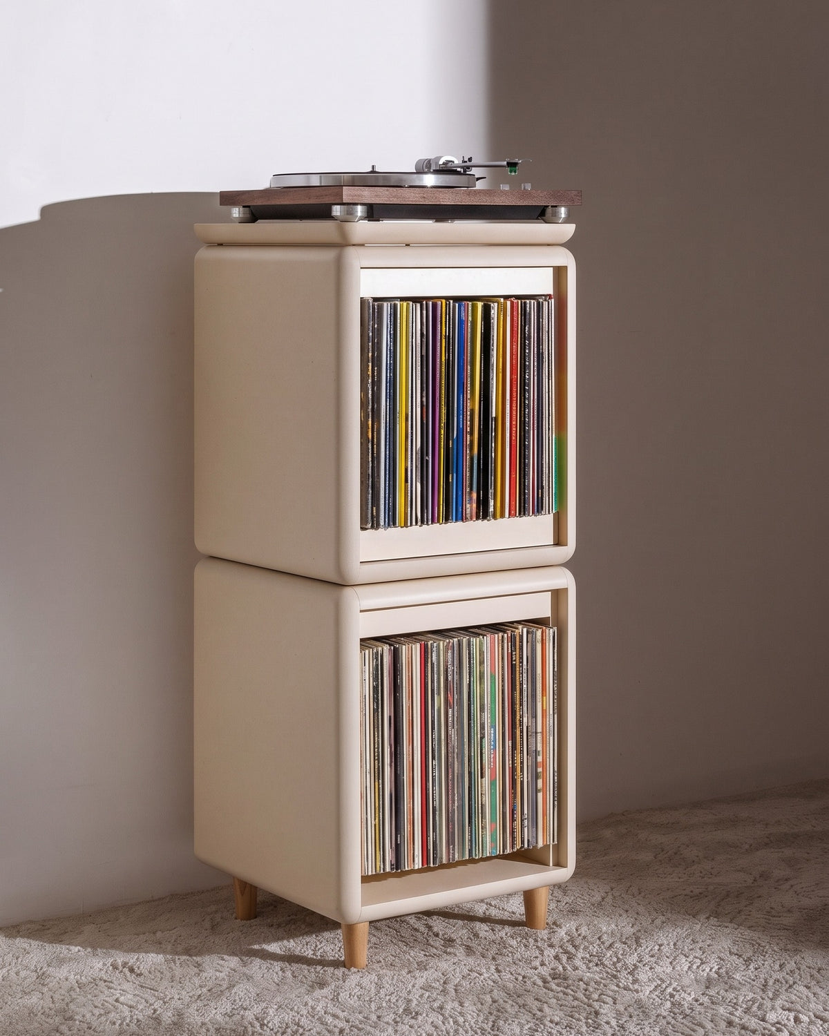 Sly vinyl furniture in White Pearl, on feet in a living room: records stored spine-out in the Bloom and Lean modules, with a turntable on top — Groovaly
