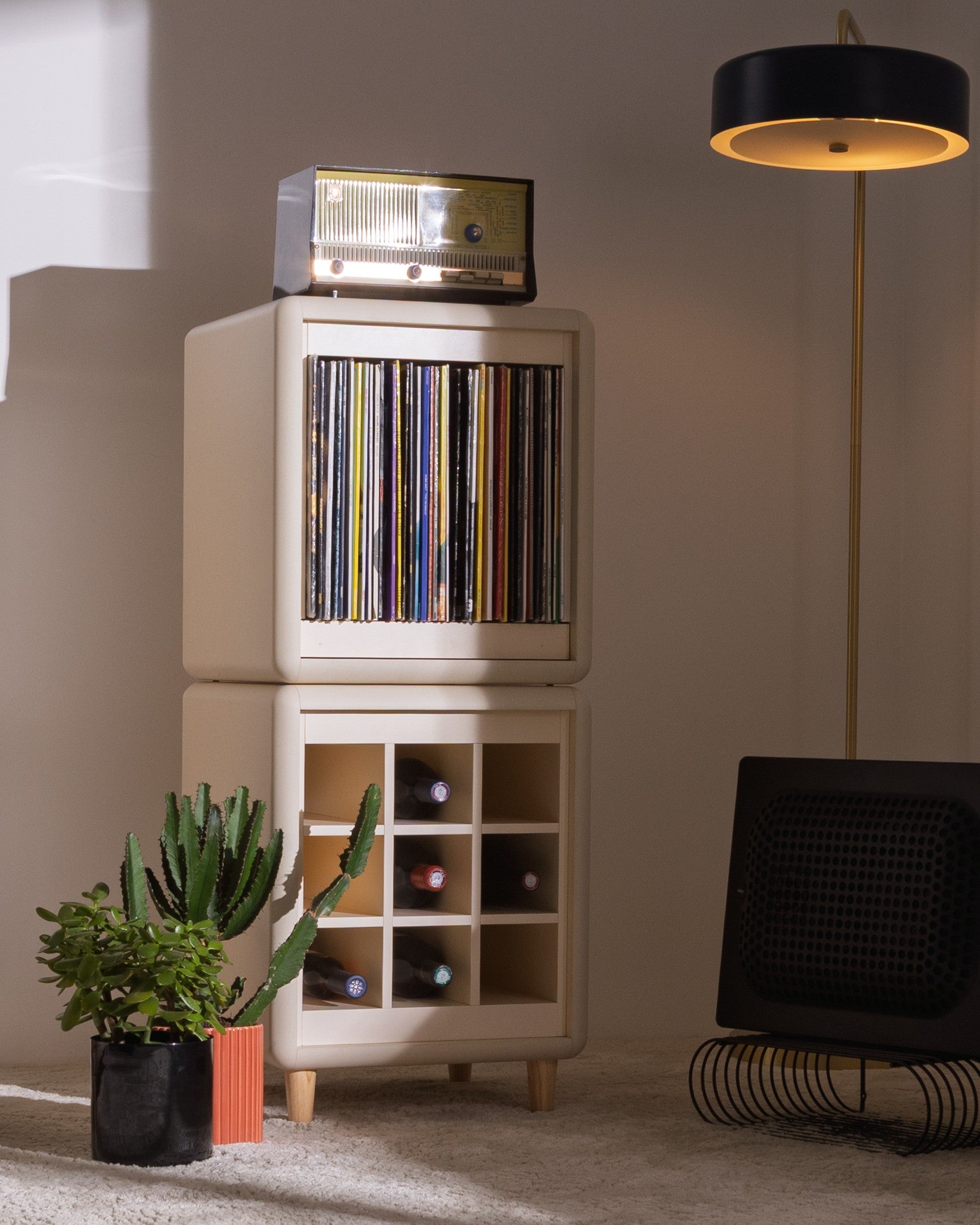 Sly in White Pearl in a warm-lit room, a vintage radio on the Bloom drawer and bottles in the Grid below — Groovaly