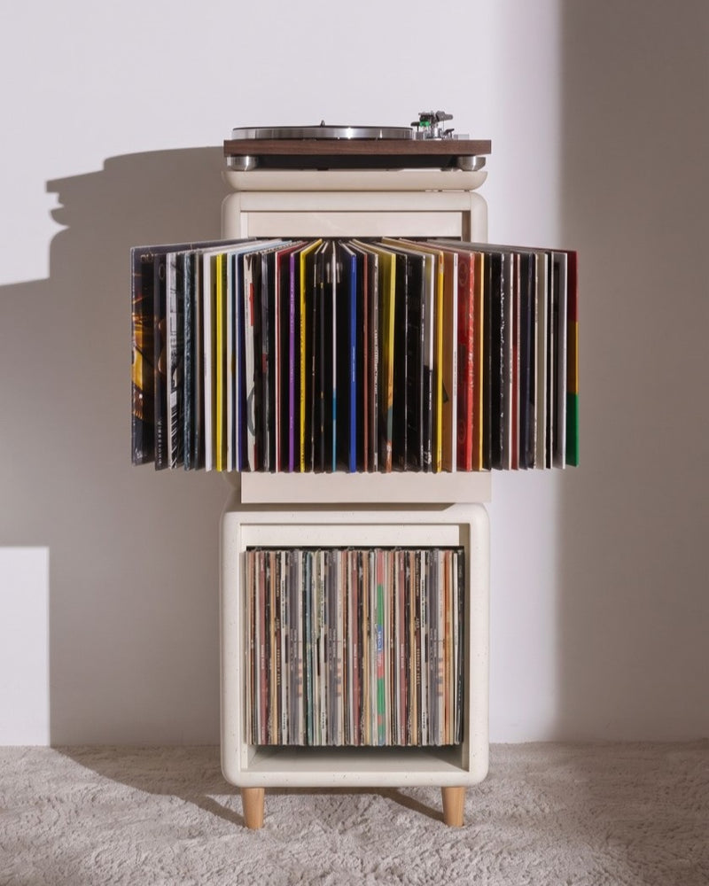 Sly vinyl furniture in White Pearl, on feet in a living room: the Bloom fan-drawer open into an arc of covers, above the Lean module, topped with a turntable — Groovaly